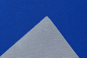 Close-up of blue PVC leather material showing textured surface and white fabric backing
