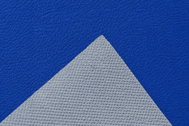 Close-up of blue PVC leather material showing textured surface and white fabric backing