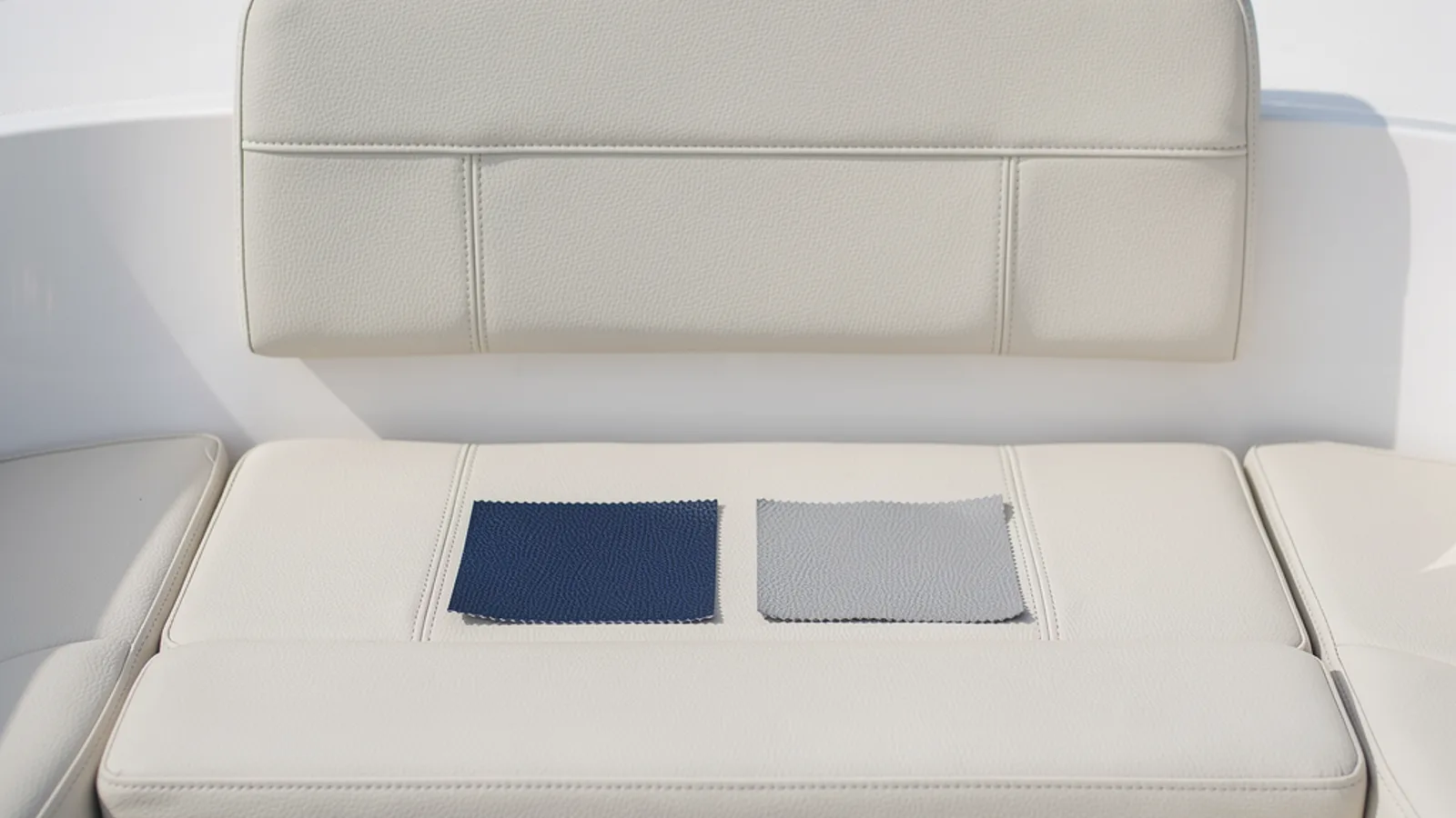 Navy and grey material swatches on a cream upholstered boat seat