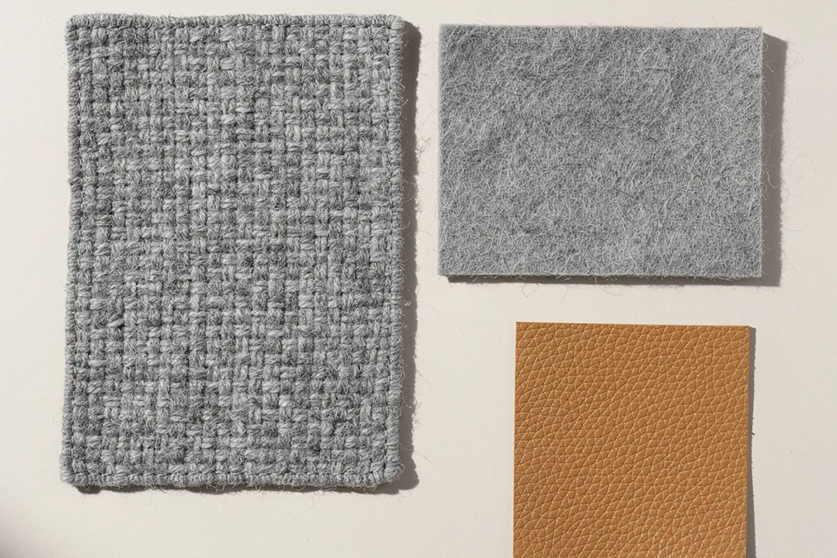 Grey woven and felt-like samples beside a tan grain-textured swatch
