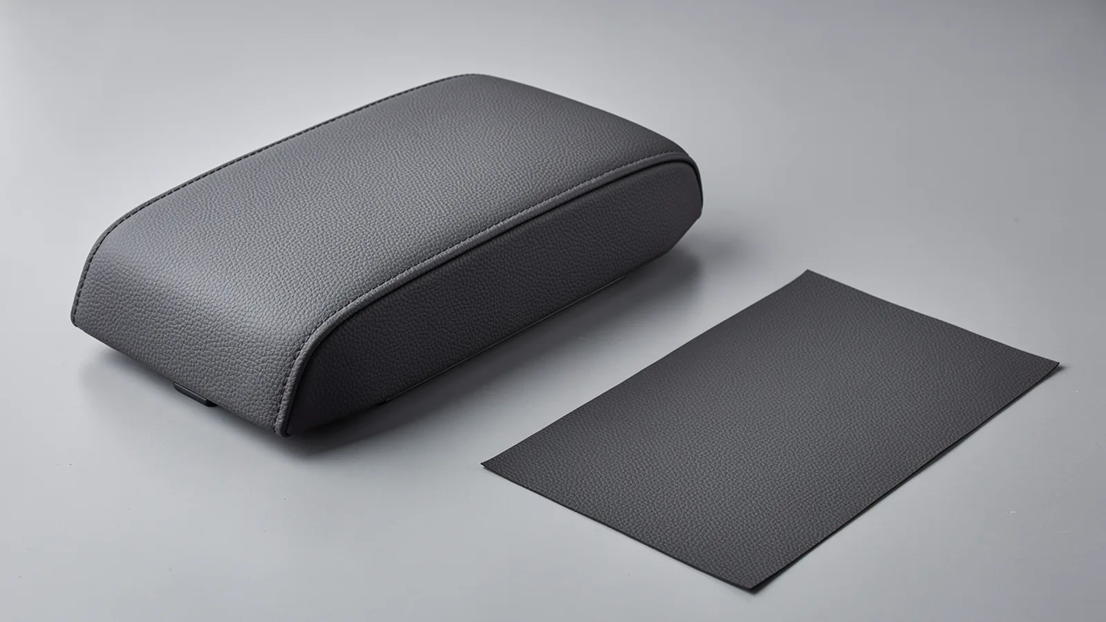 Dark gray upholstered armrest form beside a rectangular material swatch
