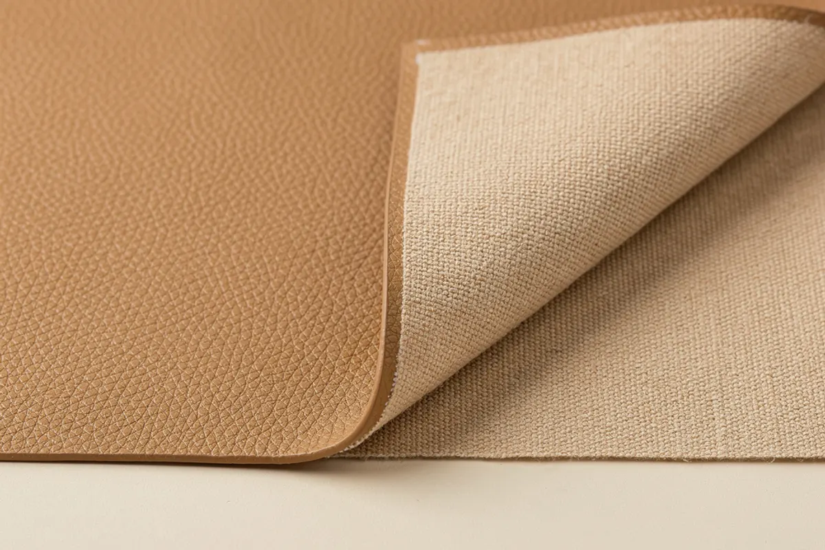 Tan coated material swatch turned back to show its beige textile backing