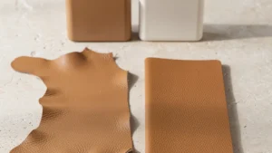 Tan material swatches beside two small accessory prototypes on a light worktable